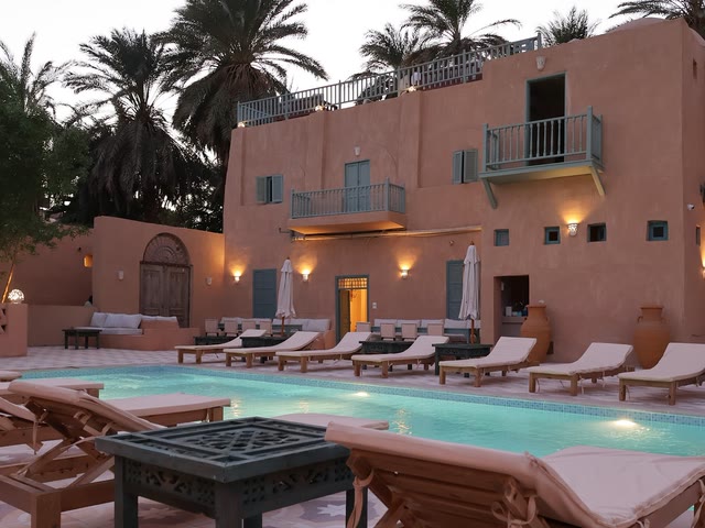 Terraço e piscina do Habu Hotel ao nascer do sol, com o Templo de Medinet Habu